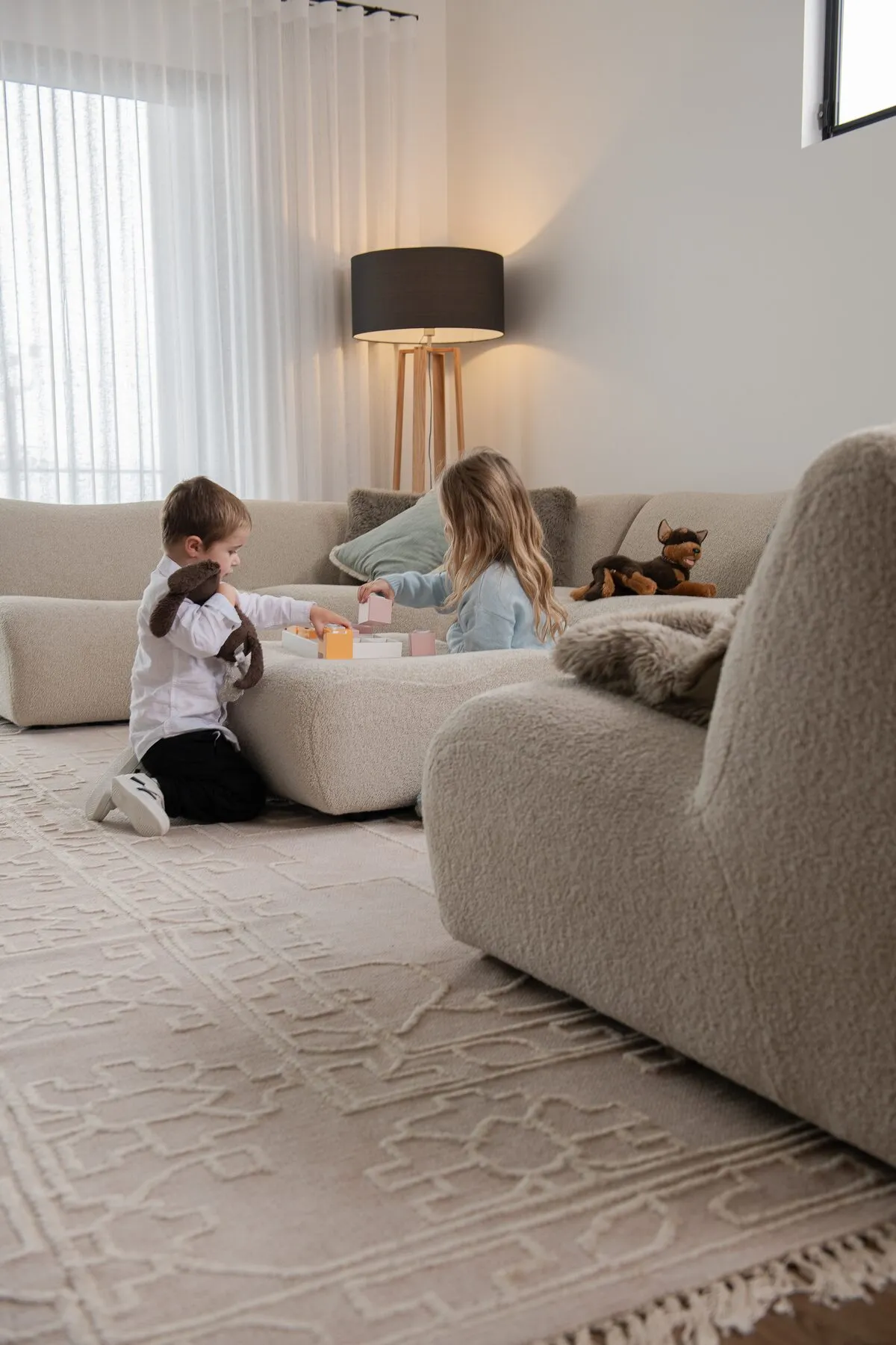 Two children playing with blocks on a rug in the open living room of a Dornford custom home